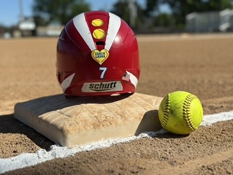 A Pistols batting helmet and softball resting on a base