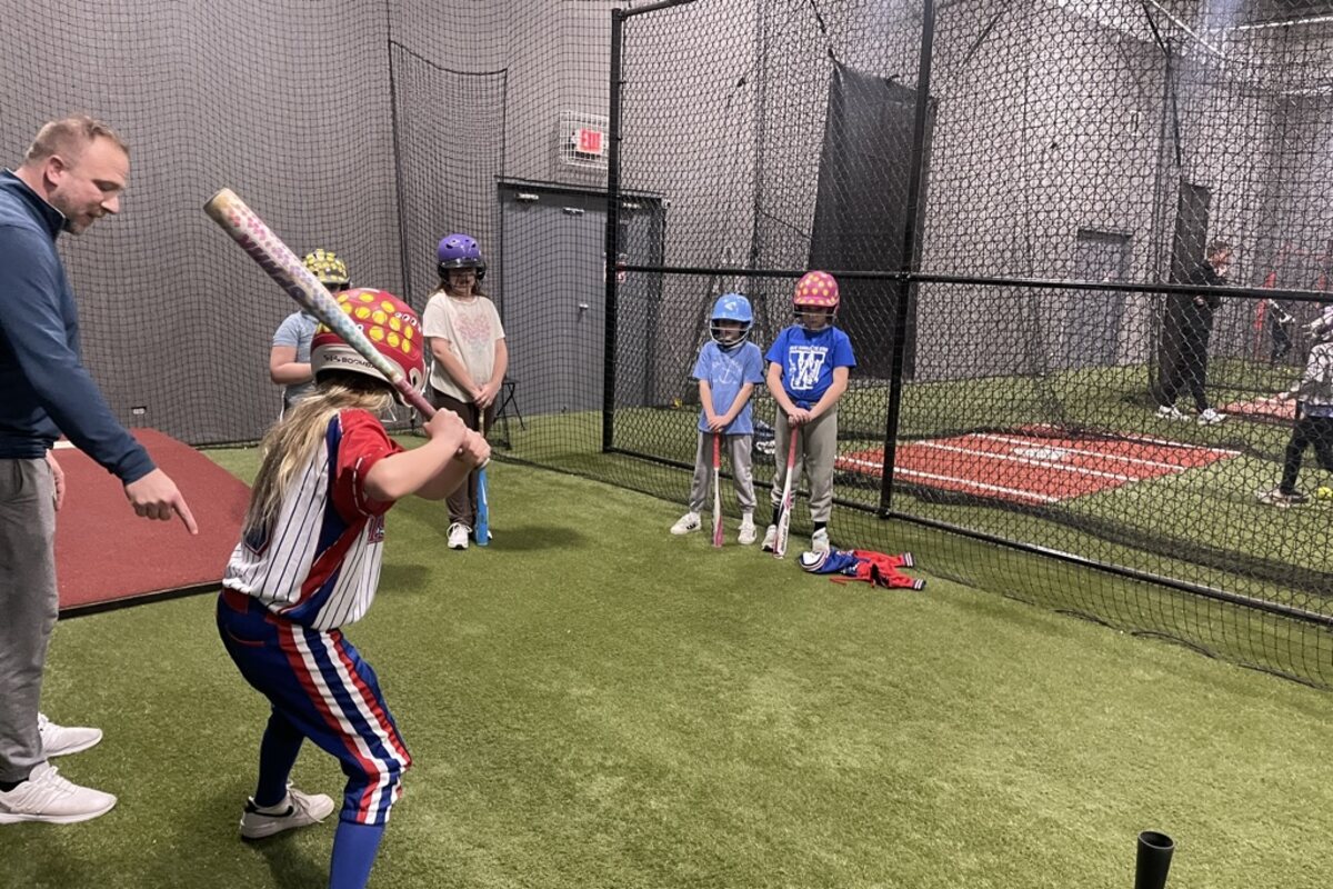 A Pistols coach working with young players in the indoor batting cage
